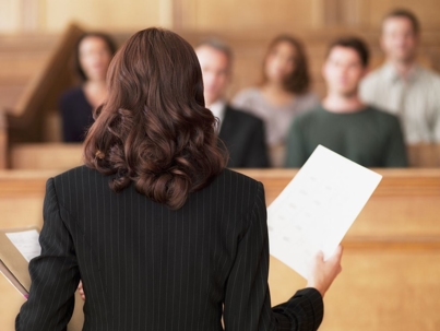 Woman standing in front of a courtroom, holding a piece of paper