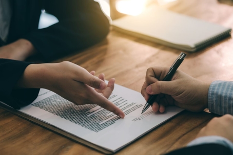 Two people sitting at table, opposite each other, working on paperwork