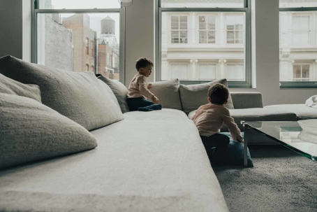 Two children at home playing on a sofa